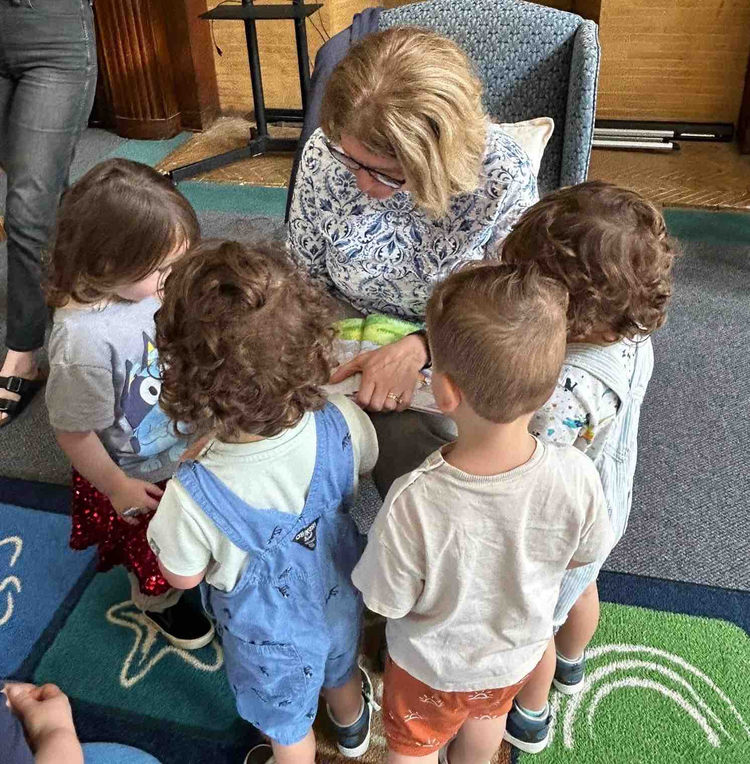 Children sitting around an adult reading a book